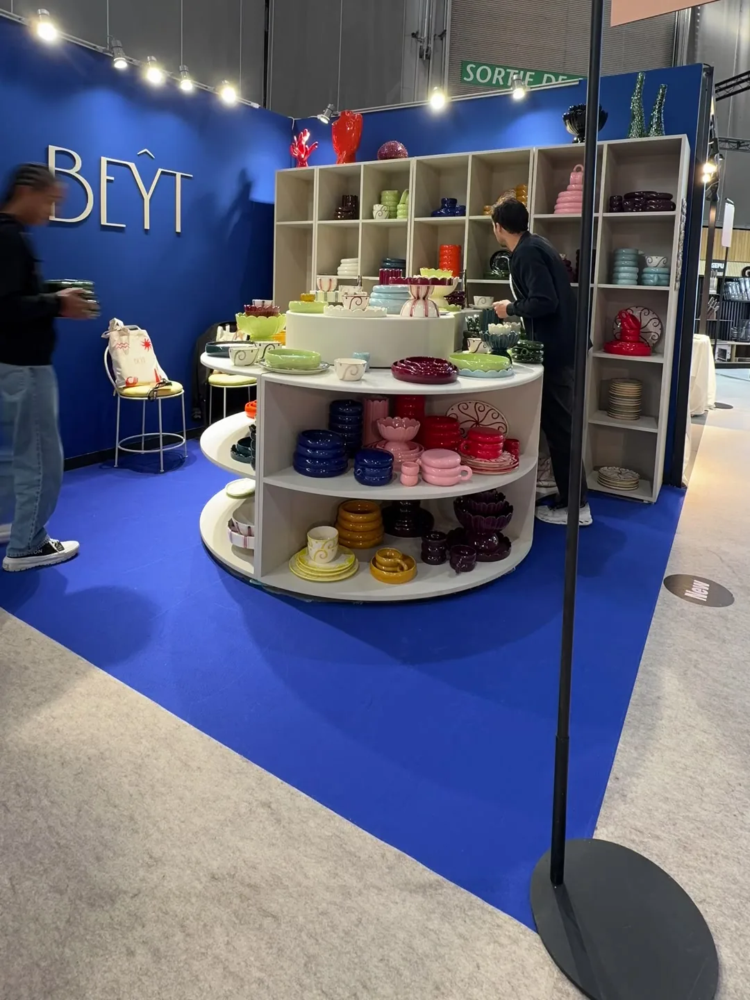 Le stand BEŶT à Maison & Objet, Hall 4 stand I58, le tapis bleu et les étagères garnies